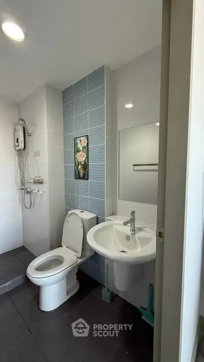 Modern bathroom with sleek fixtures and stylish blue tile accent wall.