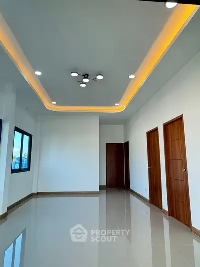 Spacious modern living room with elegant ceiling lights and wooden doors, perfect for stylish living.