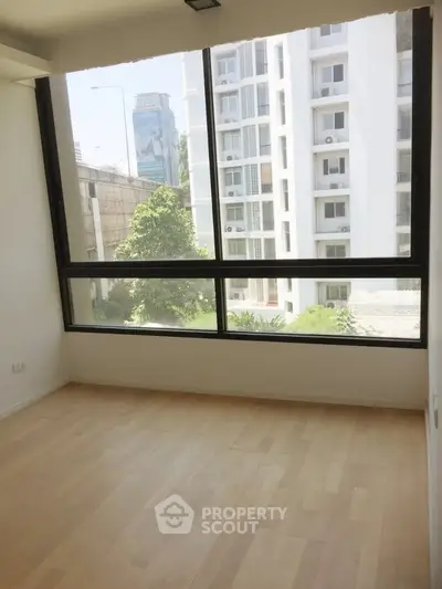 Bright empty room with large window and city view, perfect for customization.