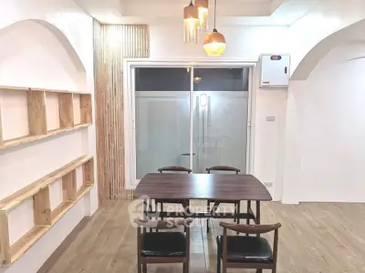 Modern dining area with wooden table, chairs, and stylish lighting in a bright, minimalist interior.