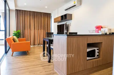 Modern living room with open kitchen, featuring stylish furniture and natural light.