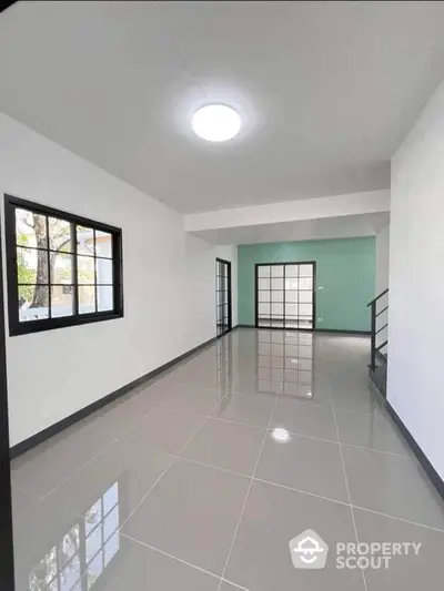 Spacious modern living room with glossy tiled floors and large windows.