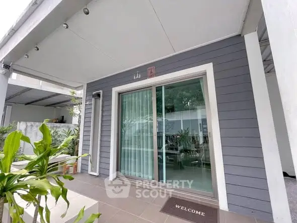 Charming modern home entrance with sliding glass doors and lush greenery.