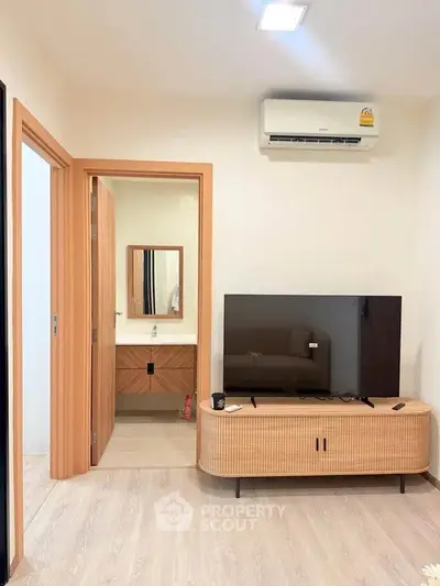 Modern living room with sleek TV stand and air conditioning, adjacent to a stylish bathroom.