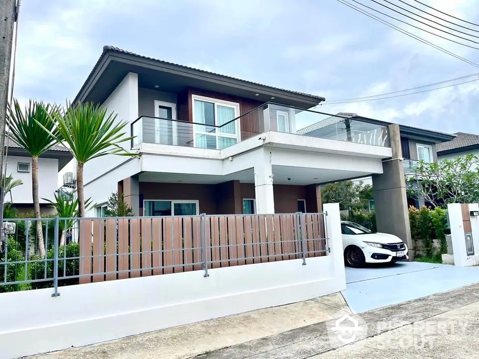 Modern two-story house with balcony and driveway in suburban neighborhood