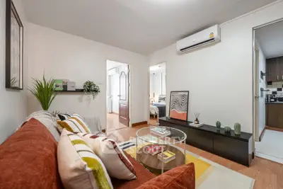 Modern living room with stylish decor and air conditioning, leading to a cozy bedroom and kitchen.