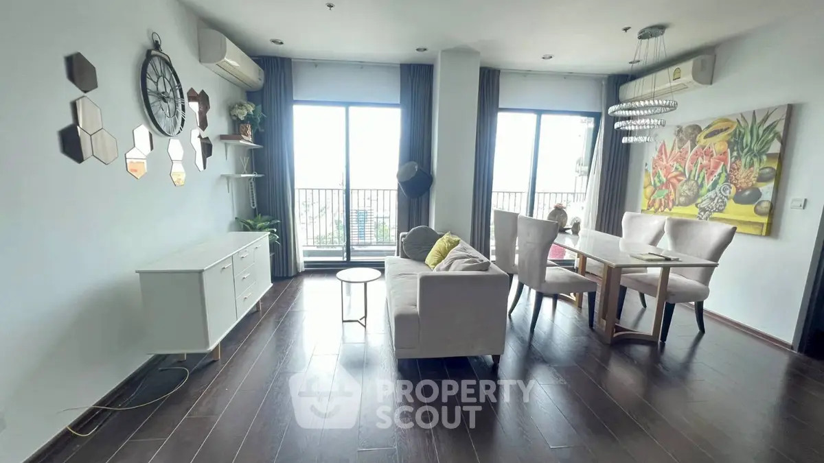 Stylish living room with modern decor and large windows offering natural light and a balcony view.