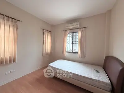 Spacious bedroom with natural light and air conditioning, featuring a comfortable bed and elegant curtains.