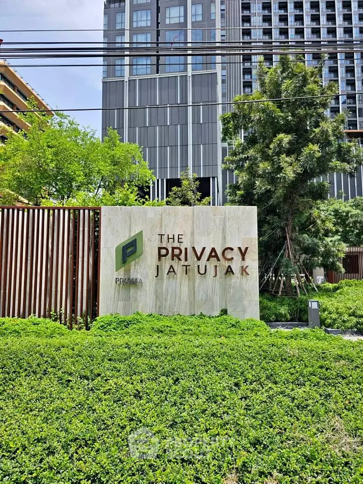 Modern condominium exterior with lush greenery at The Privacy Jatujak, showcasing urban living in a serene environment.