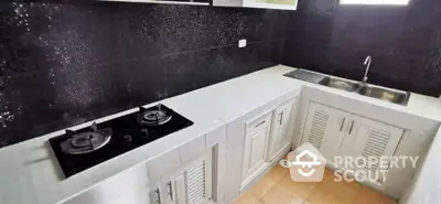 Sleek modern kitchen with black tile backsplash, white cabinetry, and built-in gas stove, perfect for culinary enthusiasts.