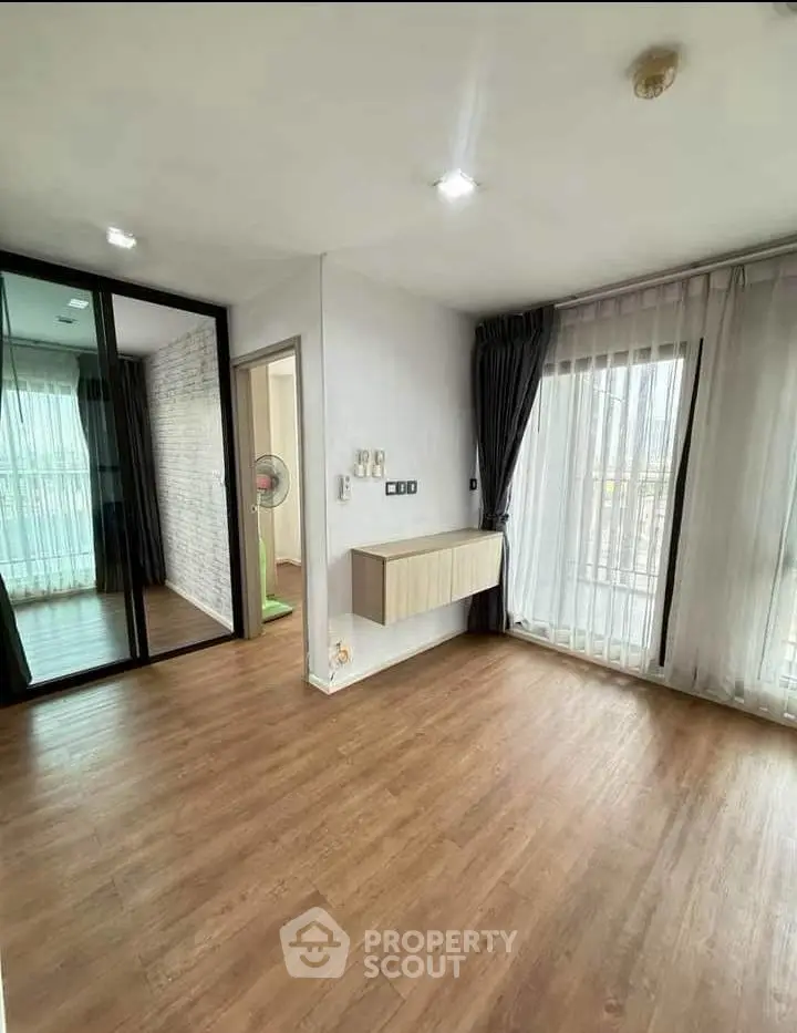 Spacious empty room with wooden flooring and large windows in modern apartment