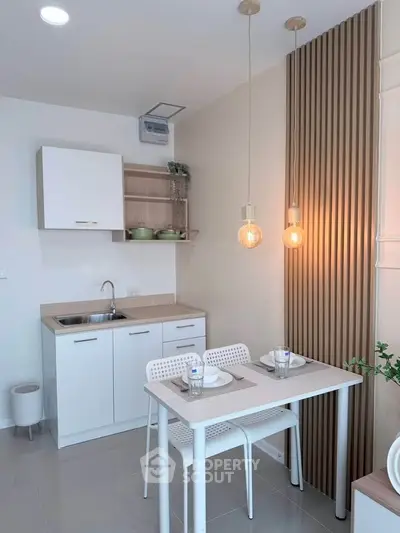 Modern compact kitchen with dining area, featuring sleek cabinetry and stylish lighting.