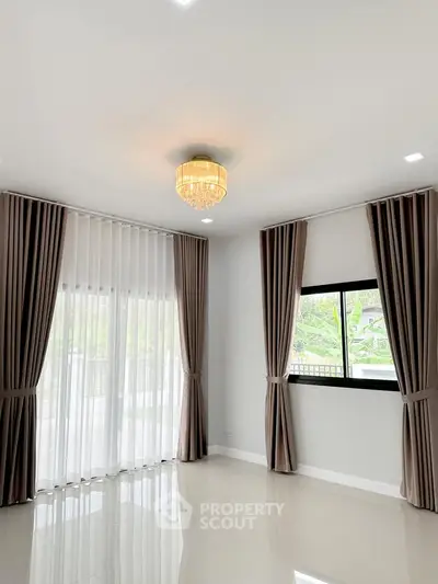 Elegant living room with modern chandelier and large windows with curtains