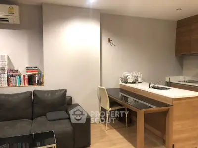 Modern open-layout living room with cozy sofa and sleek kitchen area, perfect for urban living.