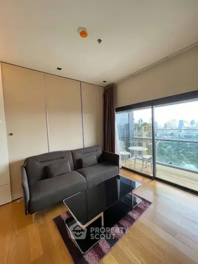 Modern living room with city view and balcony access, featuring sleek furniture and wooden flooring.