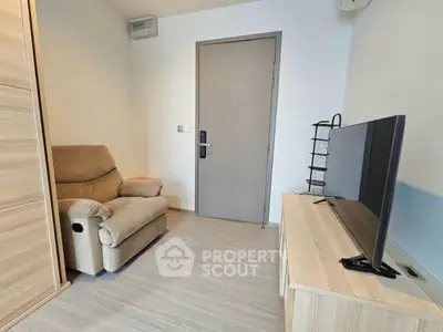 Cozy living room with modern TV setup and comfortable seating in a compact space.