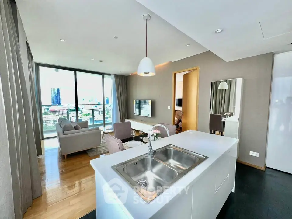 Modern open-plan living room with kitchen island and city view, featuring elegant decor and natural light.