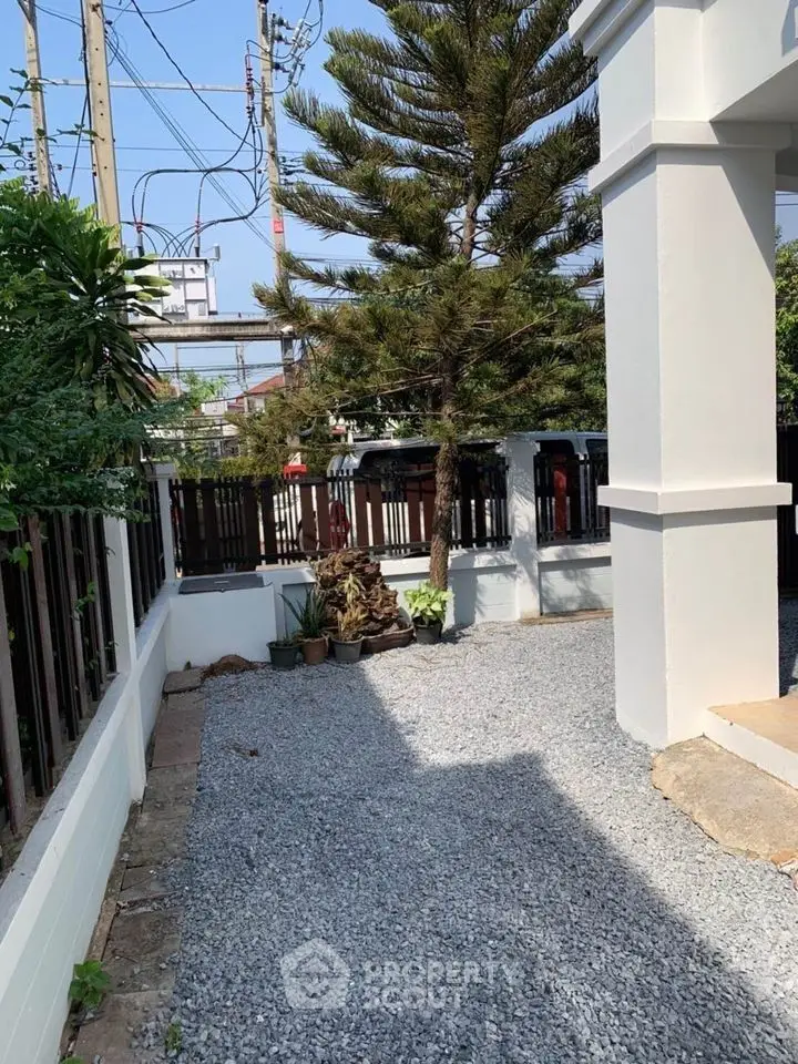 Charming exterior garden space with gravel pathway and lush greenery, perfect for outdoor relaxation.