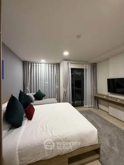 Modern bedroom with cozy bed, stylish decor, and large window for natural light.