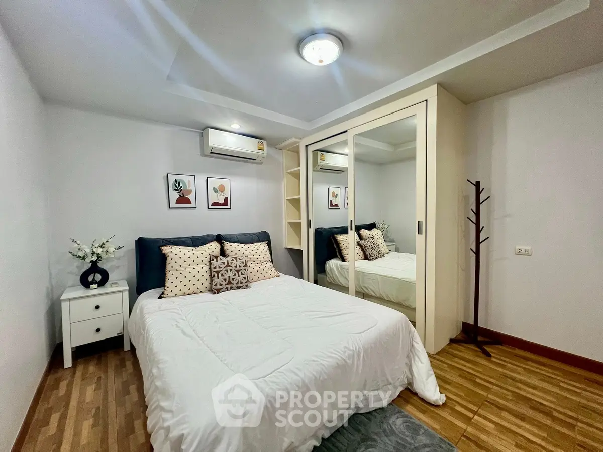 Cozy bedroom with mirrored wardrobe and stylish decor in modern apartment.