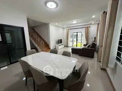 Spacious modern living and dining area with elegant marble table and cozy seating.