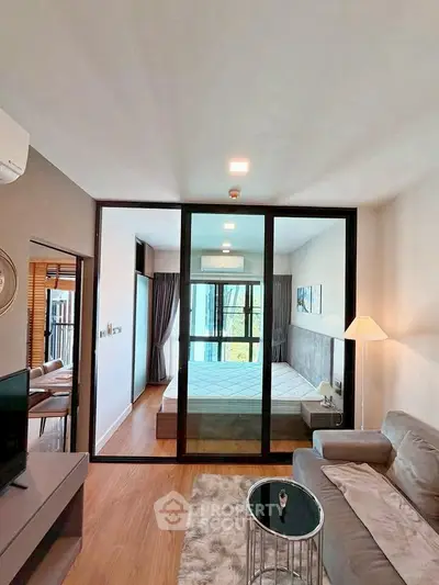 Modern apartment interior with glass partition, cozy living area, and stylish bedroom.