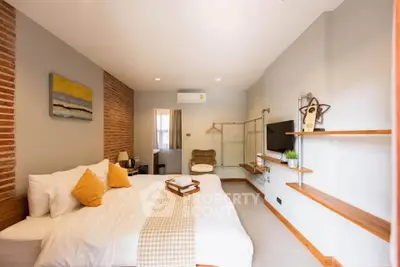 Charming bedroom with modern decor, exposed brick wall, and cozy ambiance.