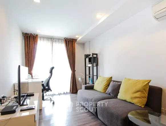 Modern living room with stylish sofa and workspace, featuring large windows and elegant curtains.