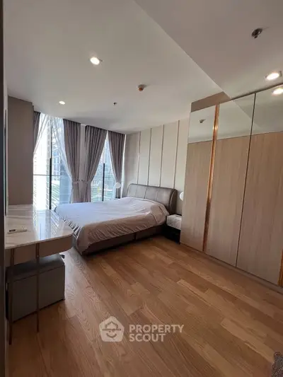 Spacious modern bedroom with large windows and wooden flooring