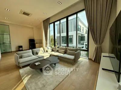 Spacious modern living room with large windows and elegant furniture, offering a bright and inviting atmosphere.