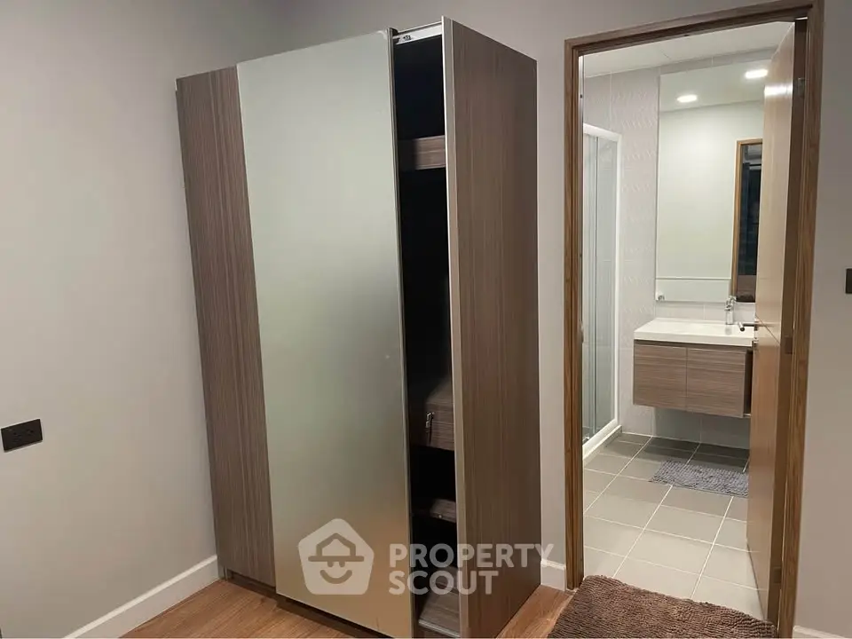 Modern interior with sleek wardrobe and bathroom view, showcasing contemporary design and functionality.