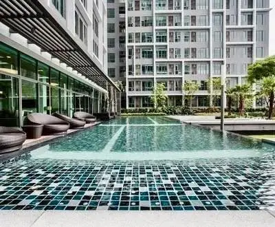 Luxurious apartment complex with modern pool and stylish outdoor seating.