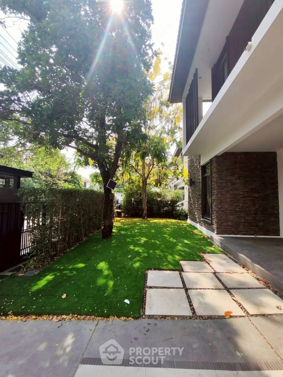 Modern home exterior with lush garden and spacious balcony, perfect for outdoor relaxation.