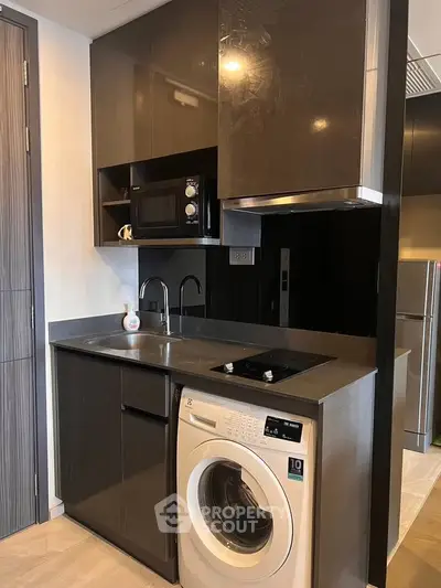 Modern compact kitchen with washing machine and microwave in sleek apartment