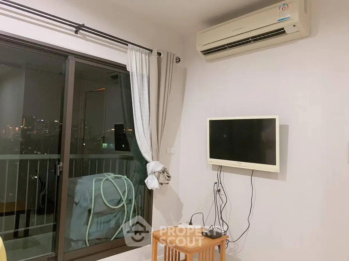 Modern living room with balcony view and wall-mounted TV in urban apartment.