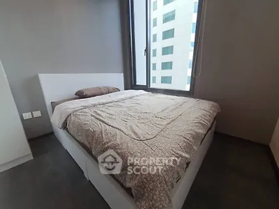 Modern bedroom with large window and stylish bed in high-rise apartment.
