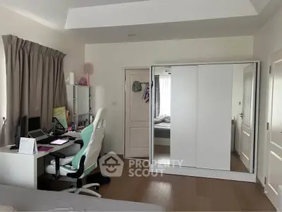 Modern bedroom with study area, featuring a sleek desk, ergonomic chair, and spacious wardrobe.