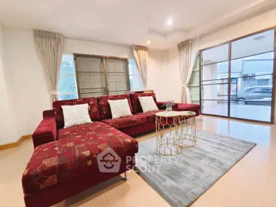 Spacious living room with elegant red sofa and modern decor in a bright, airy setting.