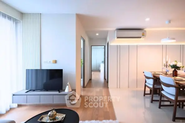 Modern living room with dining area, featuring sleek furniture and natural light.