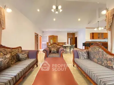Spacious living room with elegant furniture and open layout leading to dining area and kitchen.