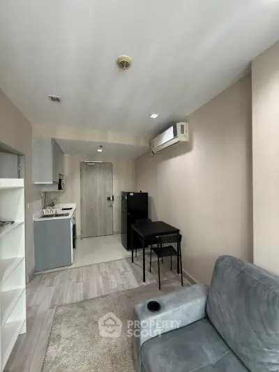 Modern compact living room with open kitchen layout and cozy furnishings.
