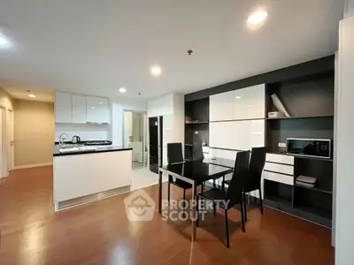Modern open-layout kitchen and dining area with sleek cabinetry and hardwood floors.