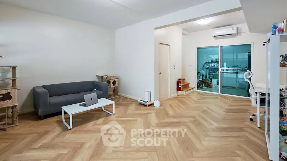 Spacious living room with modern decor and open layout, featuring herringbone flooring and a cozy sofa.