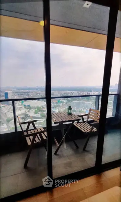 Stunning high-rise balcony with panoramic city views and cozy seating area.
