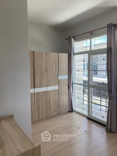 Bright bedroom with large window and modern wooden wardrobe