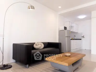 Modern living room with sleek black sofa and stylish kitchen area in open layout apartment.
