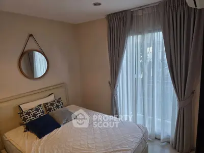 Cozy bedroom with stylish decor and natural light from large window.