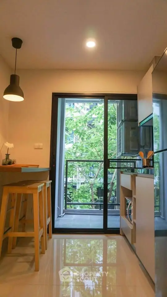 Modern kitchen with open layout and balcony view, featuring sleek cabinetry and stylish lighting.