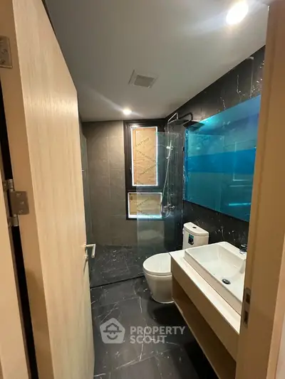 Modern bathroom with sleek black tiles and glass shower enclosure