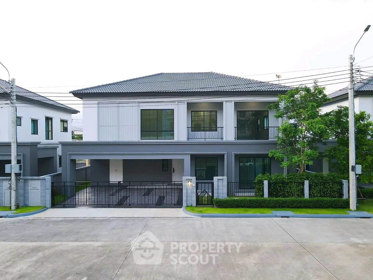 Modern two-story house with spacious driveway and lush greenery in a serene neighborhood.